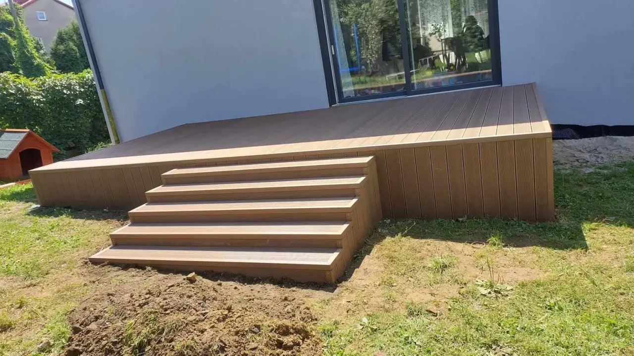 Nowy, wysoki taras ze schodami z deski kompozytowej, idealny do relaksu na świeżym powietrzu.