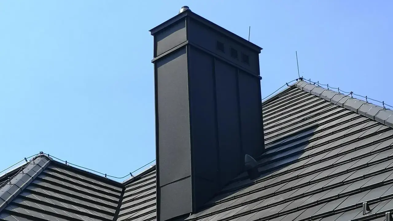 Nowoczesna obróbka blacharska komina na dachu z dachówki. Schemat montażu zapewnia estetykę i trwałość.