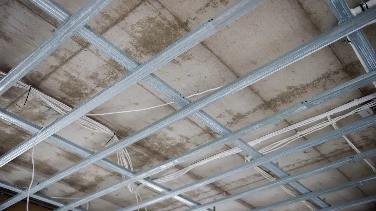 Szkielet sufitu podwieszanego podwójnego z widocznymi przewodami elektrycznymi.