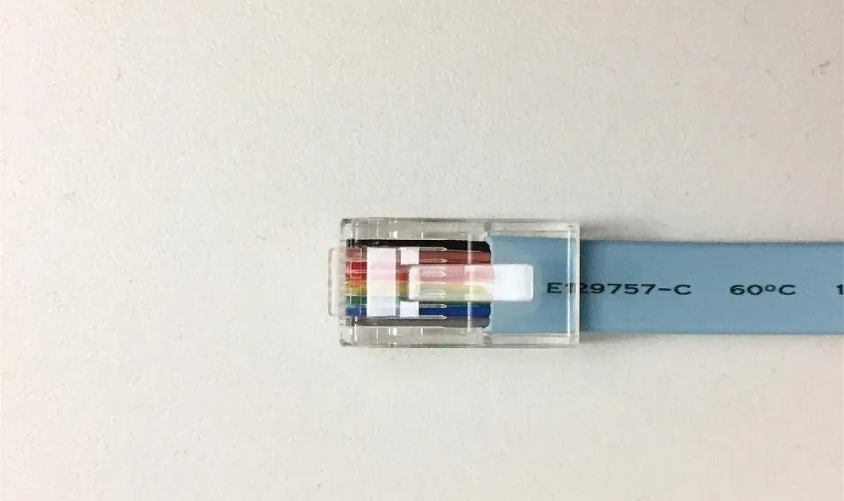 Przezroczysta wtyczka RJ45 z kolorowymi żyłkami kabla sieciowego, przypominająca budową kabel FTP a UTP.