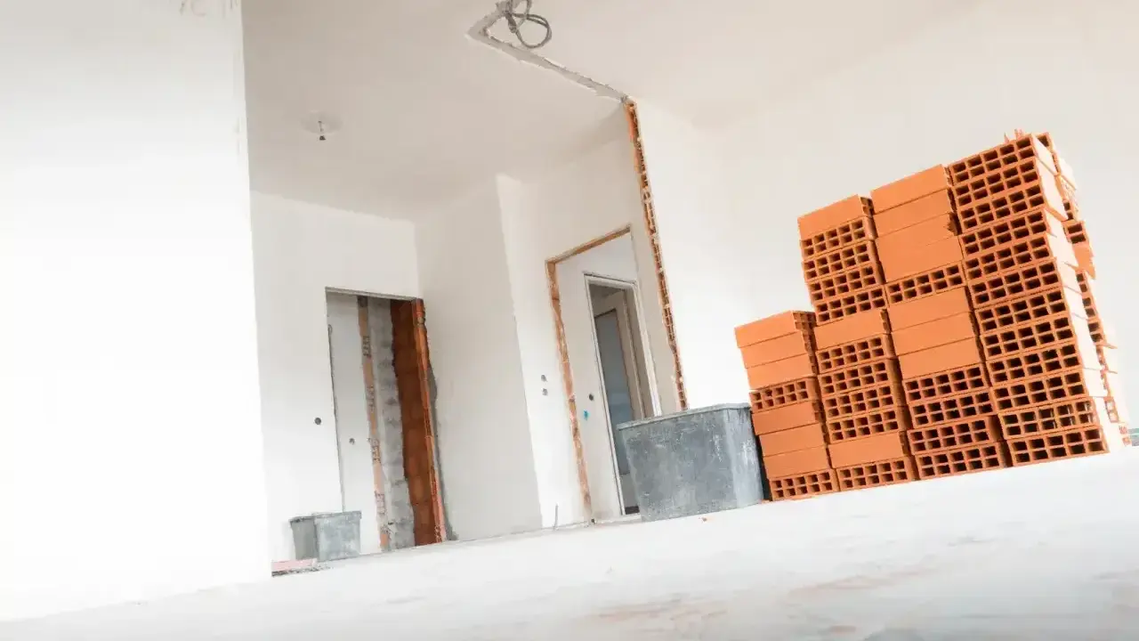 Materiały budowlane, w tym cegły, czekają na remont. Wnętrze domu w trakcie prac, przygotowanie do tego, jak wyrównać ściany w starym domu.