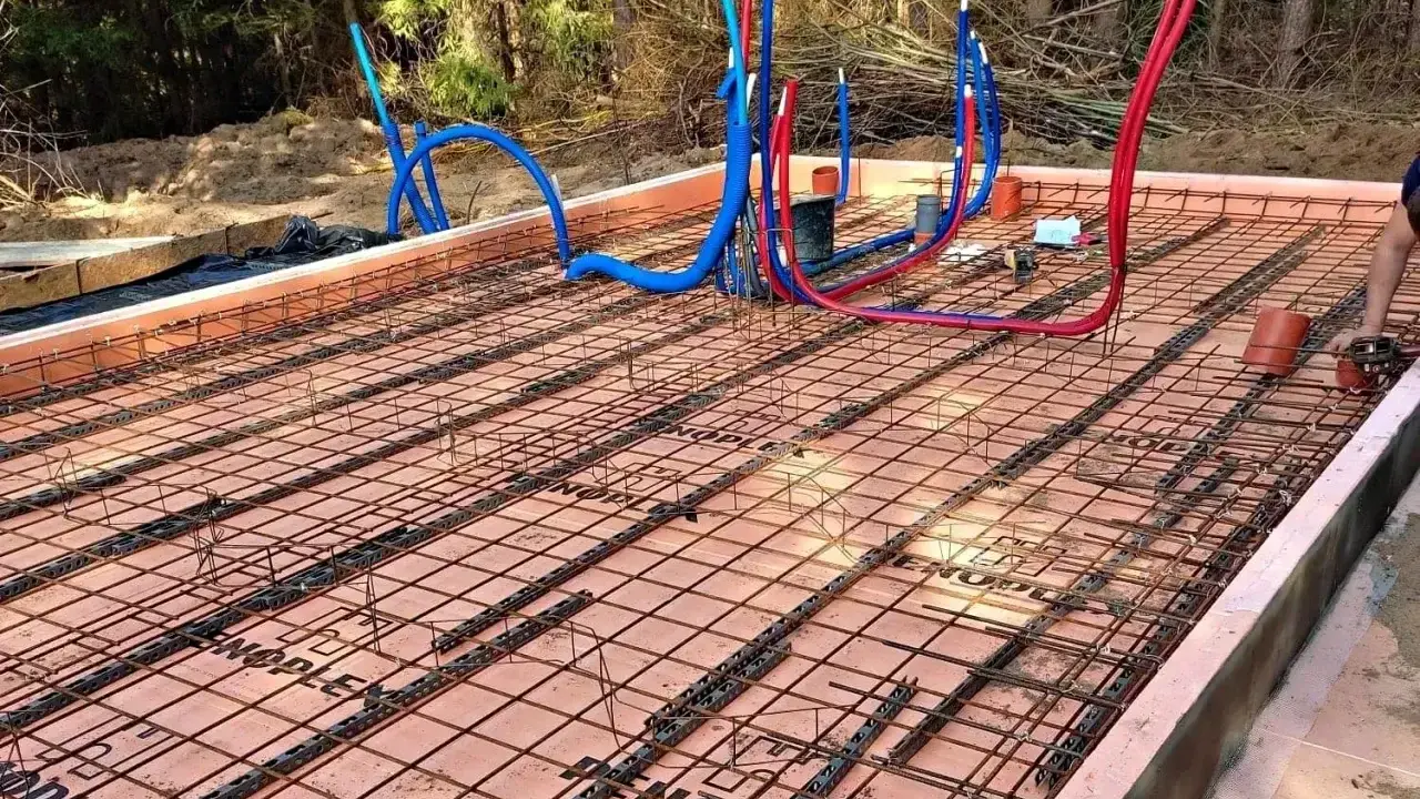 Przygotowanie do zatapiania siatki na suficie. Widoczne rury instalacyjne i zbrojenie pod wylewkę.