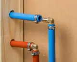 Instalacja hydrauliczna: przejście z tece na pex. Niebieskie i pomarańczowe rury PEX połączone złączkami mosiężnymi.