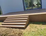 Nowy, wysoki taras ze schodami z deski kompozytowej, idealny do relaksu na świeżym powietrzu.
