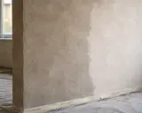 Ściana z tynkiem w trakcie schnięcia. Widać wyraźną różnicę między świeżo nałożoną warstwą a tą, która już zaczyna wysychać. Czekamy, aż tynki schną.