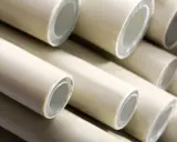 Zbliżenie na stos jasnych, plastikowych rur z widocznymi przekrojami.