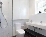Nowoczesna łazienka z prysznicem, WC i podwójną umywalką. Jak zabudować rurę od WC? Tutaj widać, jak estetycznie ukryto instalację.