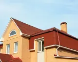 Dachówka i komin na domu z cegły. Mansarda co to? To przestrzeń pod dachem, często z oknami.