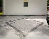 Nowoczesne układanie kostki na grysie z geometrycznym wzorem. Wjazd do domu z szarej kostki.