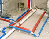 Skomplikowana instalacja wodna w karton gipsie, z rurami w kolorach czerwonym, niebieskim i białym, gotowa do ukrycia.
