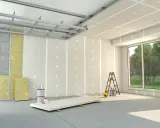 Budowa wnętrza: stelaż drewniany pod gk, płyty gipsowo-kartonowe, wełna mineralna, drabina i materiały budowlane.