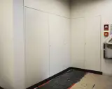 Nowoczesna zabudowa szachtu w bloku, z białymi drzwiami i dyskretnymi uchwytami. Na ścianie widoczny alarm przeciwpożarowy.
