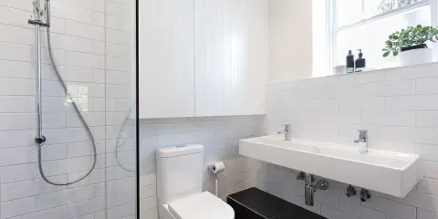 Nowoczesna łazienka z prysznicem, WC i podwójną umywalką. Jak zabudować rurę od WC? Tutaj widać, jak estetycznie ukryto instalację.