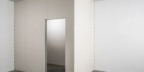 Narożnik pomieszczenia z nową scianką działową z płyty kartonowo gipsowej, z widocznym otworem drzwiowym.