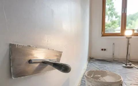 Idealna ściana po gładzi jest gładka i równa. Na zdjęciu widać narzędzie do jej wygładzania.