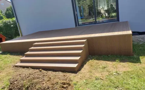 Nowy, wysoki taras ze schodami z deski kompozytowej, idealny do relaksu na świeżym powietrzu.