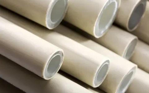 Zbliżenie na stos jasnych, plastikowych rur z widocznymi przekrojami.