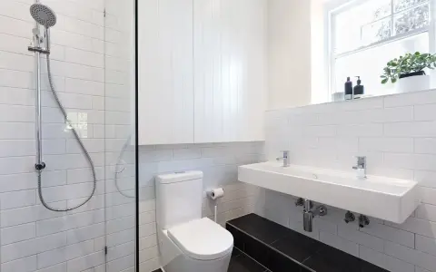 Nowoczesna łazienka z prysznicem, WC i podwójną umywalką. Jak zabudować rurę od WC? Tutaj widać, jak estetycznie ukryto instalację.