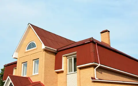 Dachówka i komin na domu z cegły. Mansarda co to? To przestrzeń pod dachem, często z oknami.