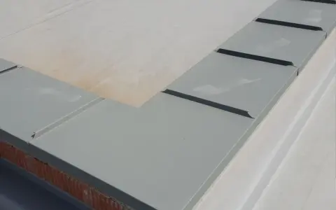 Szary parapet dachowy, element montażu rynien plastikowych, zabezpiecza mur przed wilgocią.