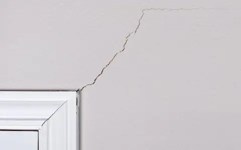 Pęknięcia na suficie akryl, widoczne nad białym gzymsem, tworzą nieregularny wzór.