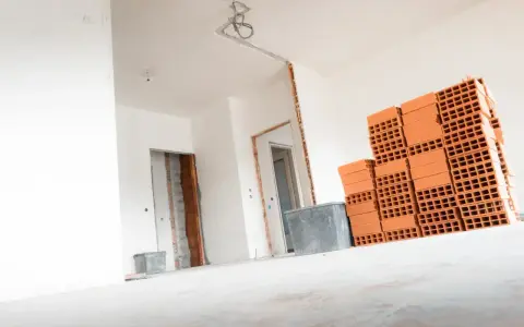 Materiały budowlane, w tym cegły, czekają na remont. Wnętrze domu w trakcie prac, przygotowanie do tego, jak wyrównać ściany w starym domu.