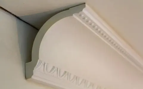 Widok z bliska na narożnik sufitu z elementami dekoracyjnymi i widocznym stelażem pod karton gips sufit.