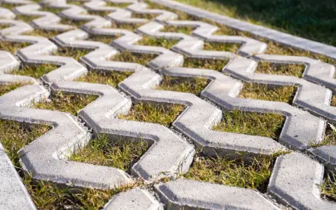 Szary beton na płyty ażurowe, z trawą rosnącą między elementami. Idealny na podjazd.