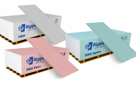 Karton gips do łazienki: zielone płyty Rigips PRO Hydro, różowe PRO Fire+ i szare PRO na paletach.