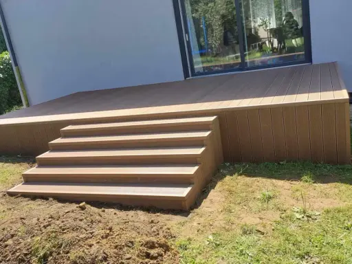 Nowy, wysoki taras ze schodami z deski kompozytowej, idealny do relaksu na świeżym powietrzu.