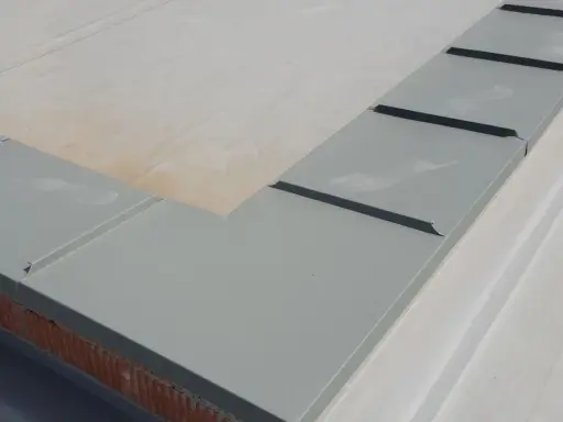 Szary parapet dachowy, element montażu rynien plastikowych, zabezpiecza mur przed wilgocią.