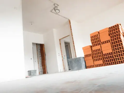 Materiały budowlane, w tym cegły, czekają na remont. Wnętrze domu w trakcie prac, przygotowanie do tego, jak wyrównać ściany w starym domu.