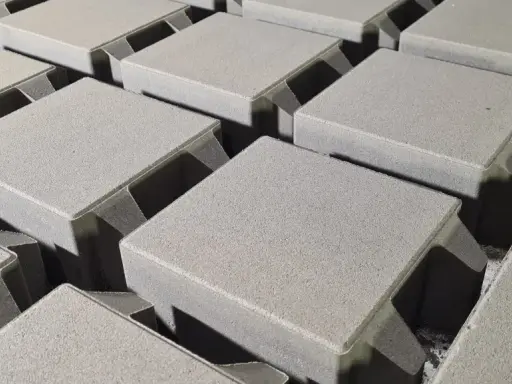 Szare kostki brukowe ułożone w rzędach, niektóre z fazowanymi krawędziami.