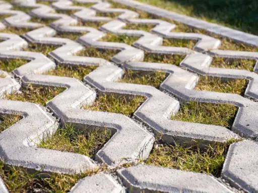 Szary beton na płyty ażurowe, z trawą rosnącą między elementami. Idealny na podjazd.