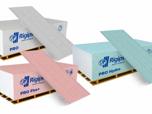 Karton gips do łazienki: zielone płyty Rigips PRO Hydro, różowe PRO Fire+ i szare PRO na paletach.