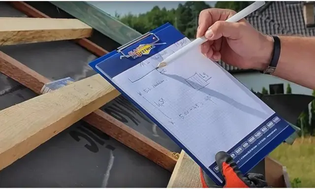 Rysunki na notesie pokazują, jak wymierzyć dach kopertowy. Obliczenia na papierze pomagają w pracach dekarskich.