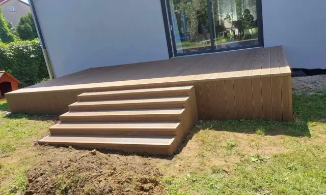 Nowy, wysoki taras ze schodami z deski kompozytowej, idealny do relaksu na świeżym powietrzu.