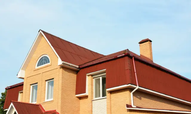 Dachówka i komin na domu z cegły. Mansarda co to? To przestrzeń pod dachem, często z oknami.