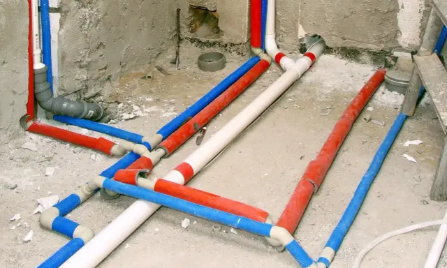 Skomplikowana instalacja wodna w karton gipsie, z rurami w kolorach czerwonym, niebieskim i białym, gotowa do ukrycia.