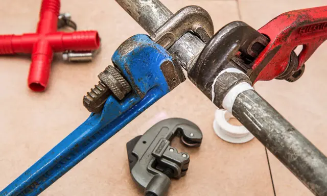 Narzędzia hydrauliczne i czerwony trójnik. Zastanawiasz się, czym zakleić dziury po hydrauliku? Taśma teflonowa i klucze nastawne pomogą.