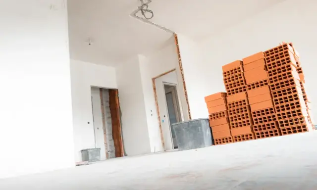 Materiały budowlane, w tym cegły, czekają na remont. Wnętrze domu w trakcie prac, przygotowanie do tego, jak wyrównać ściany w starym domu.