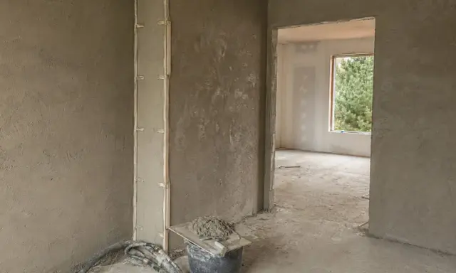 Ściany pokryte tynkami cementowo wapiennymi, przygotowane do dalszych prac. Widać wiadro z zaprawą i narzędzia.