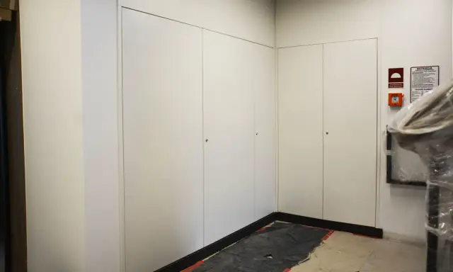 Nowoczesna zabudowa szachtu w bloku, z białymi drzwiami i dyskretnymi uchwytami. Na ścianie widoczny alarm przeciwpożarowy.