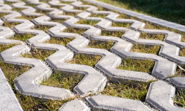 Szary beton na płyty ażurowe, z trawą rosnącą między elementami. Idealny na podjazd.